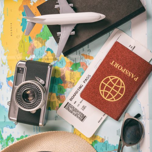 Travel and vacation accessories, map background. Voyage for tourism, business with essentials, tickets, passport, book, camera, eyeglasses, hat. Vertical, top view.